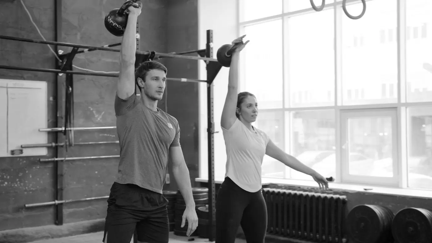 Dupla treinando kettlebell perto da janela