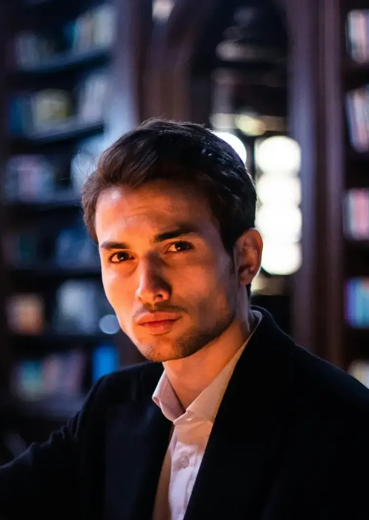 Otávio Faraco, sócio, sentado à mesa do escritório com luz de luminária