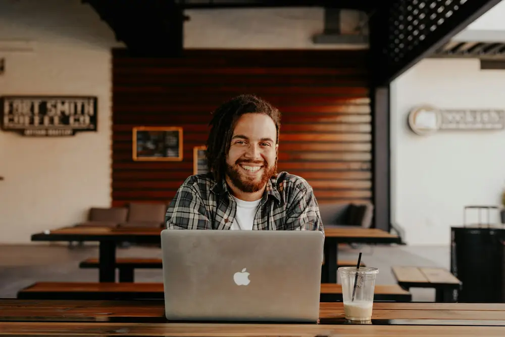Lucas, desenvolvedor, sorrindo em frente ao notebook numa cafeteria