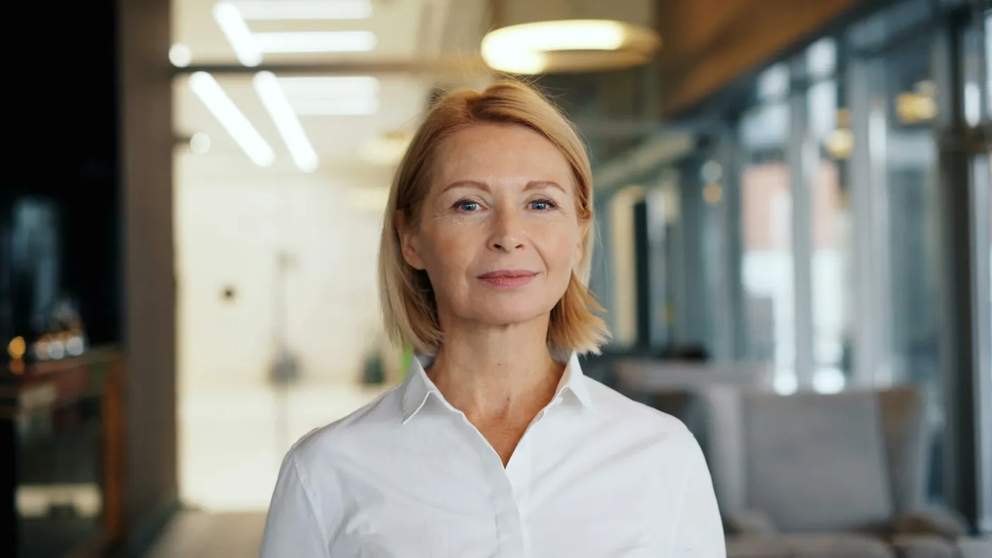 Helena Rothbarth, corretora e sócia, de camisa branca em um living iluminado