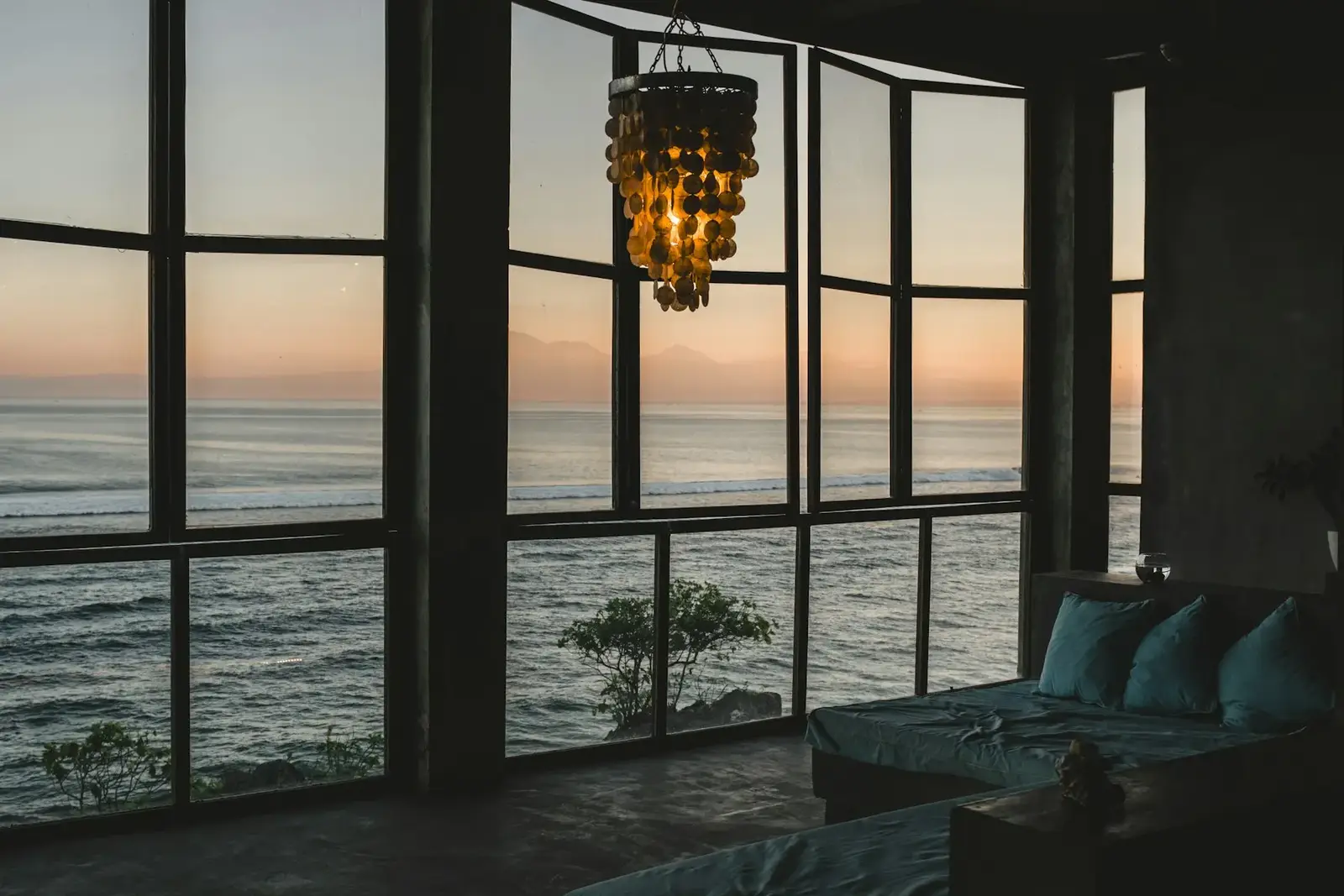 Sala com janelões abertos para o mar ao entardecer