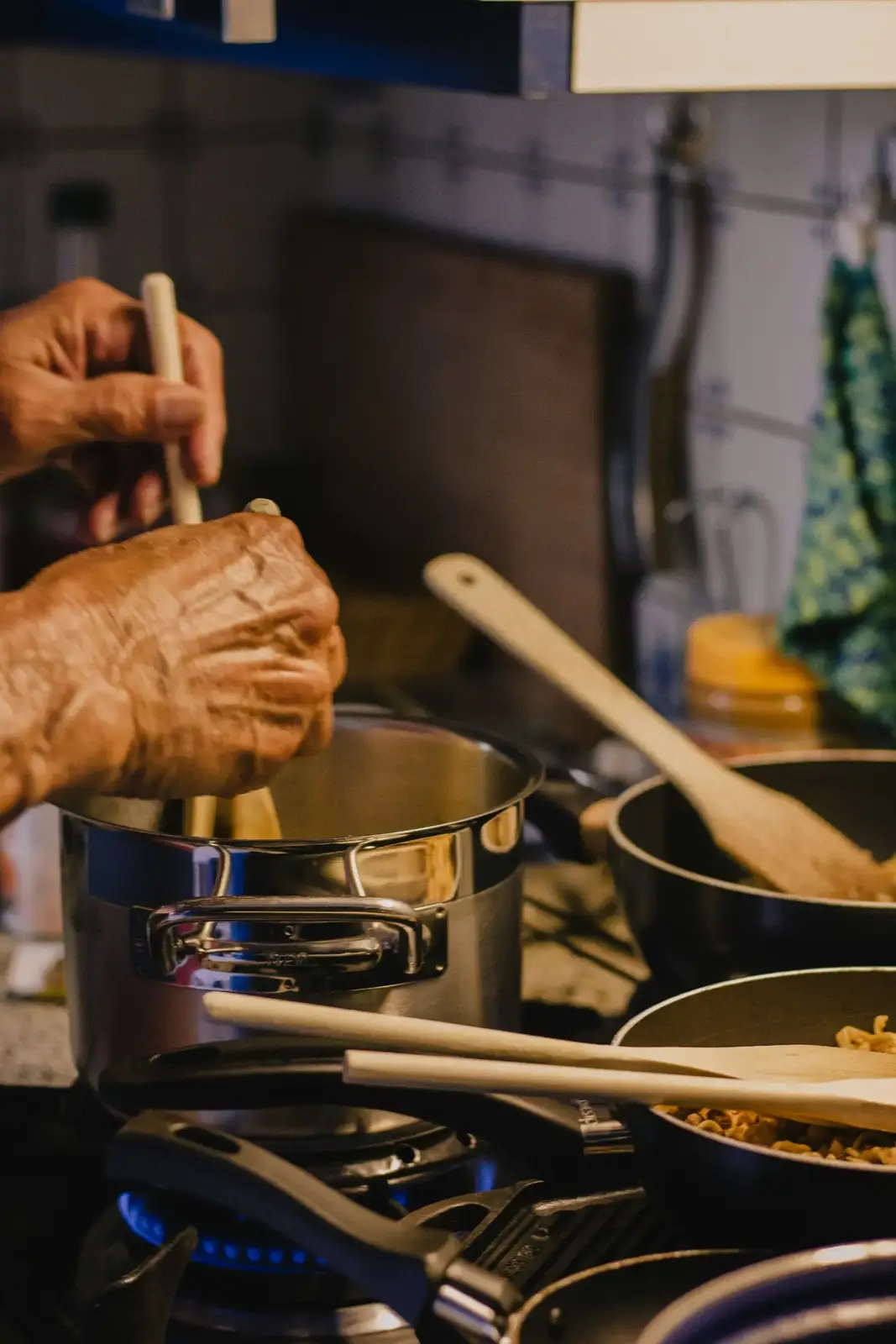 Mãos mexendo panelas no fogão da cozinha