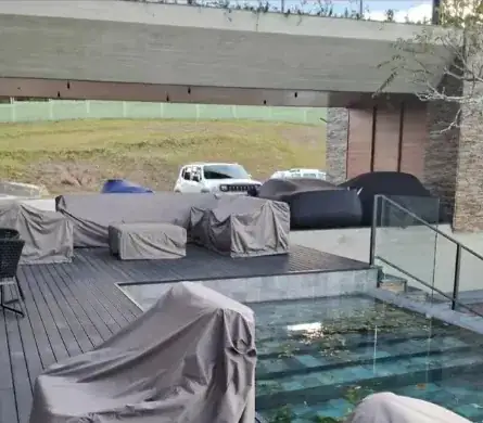 Deck de madeira ao lado da piscina com vários móveis cobertos por capas taupe sob medida