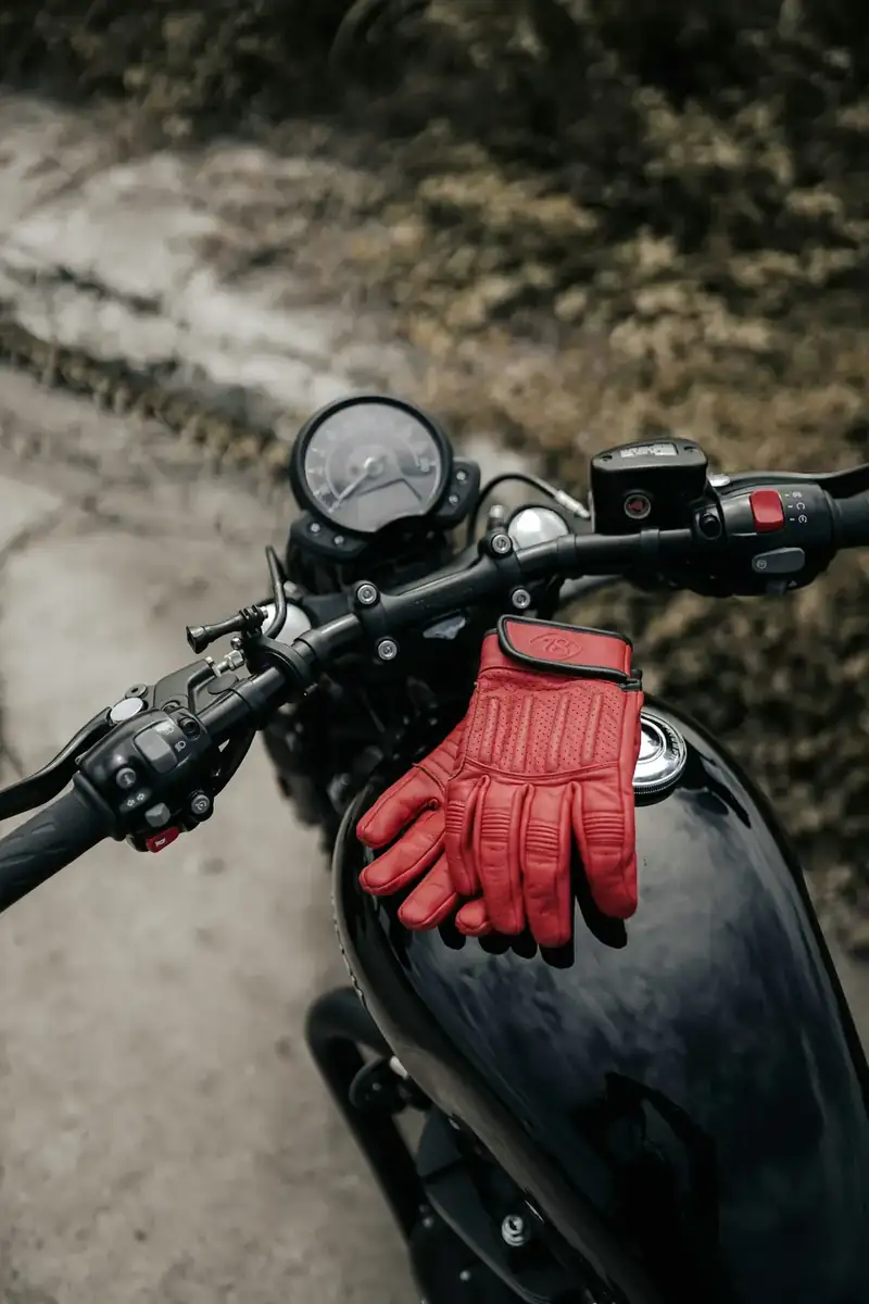 Luvas vermelhas de motociclista apoiadas no tanque de uma moto preta